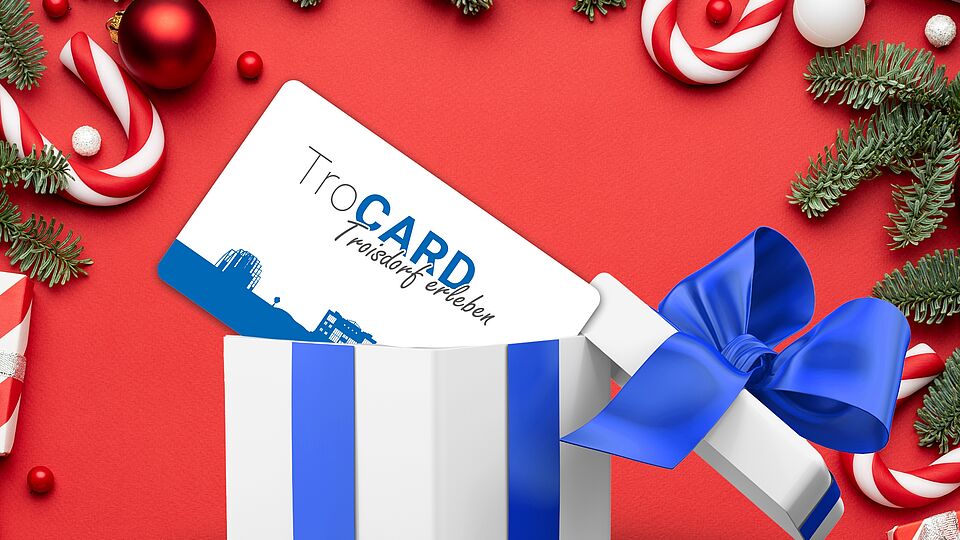 TroCARD in Geschenkebox vor weihnachtlicher roter Kulisse