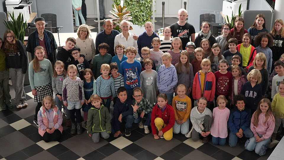 Gruppenbild von zahlreichen Kindern und Jugendlichen der Sommerkunstschule 2024 gemeinsam mit der Schauspieler und professionelle Geschichtenerzähler Peter Glass, Stadtwerke-Geschäftsführerin Andrea Vogt sowie Masoud Sadedin und Jette Jertz von der Troisdorfer KreativWerkstatt im Kundenzentrum des Lokalversorgers. ünst-lern der diesjährigen Sommerkunstschule, um gemeinsam das Finale der Ausstellung „Glück hat viele Farben“ in der Stadtwerke-Galerie zu feiern. 